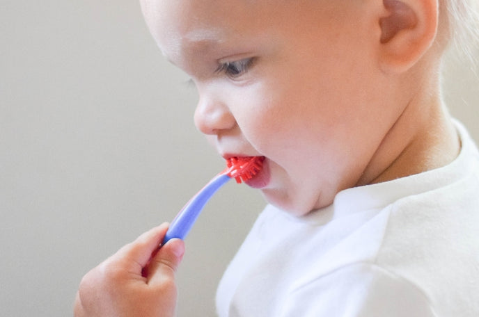 Young child using one of the brushes from Nuby's 4-Stage Oral Care System.