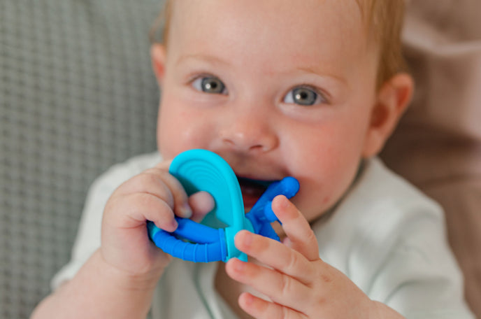 Happy baby chewing on a Nuby teething toy.