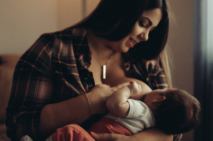 A young woman breastfeeding her infant child.