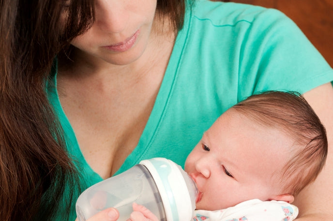 Mother feeding her infant child with a Nuby Comfort 360° Anti-Reflux & Anti-Colic Bottle.