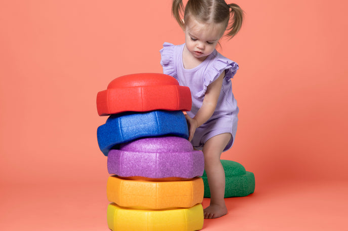 Child playing with Nuby StepPebble stepping stones, stacking them up to create a colorful tower.