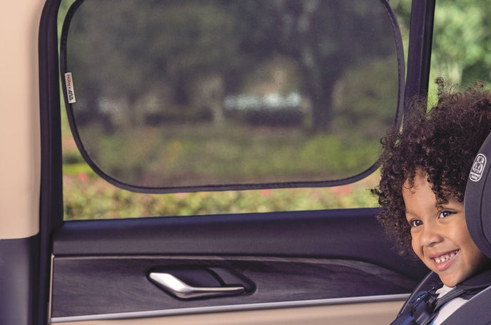 Toddler in forward facing car seat with Nuby x Safe in the Seat window screen.