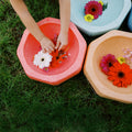 Children arrange flowers in a water-filled orange basin beside blue and beige basins with floating blooms and foam stepping stones on grass. Perfect for indoor or outdoor play with StepPebbles and FREE Balance Board | Pastel set.