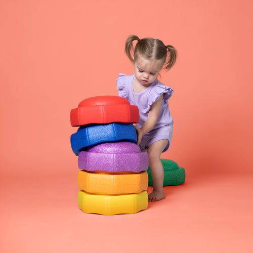 Toddler holding a Nuby StepPebbles toy, stacked up.