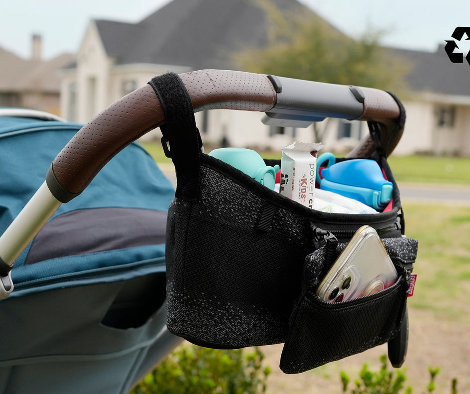 Nuby Eco Stroller Organizer attached to a stroller. The recycling symbol is in the upper-right corner of the image. 