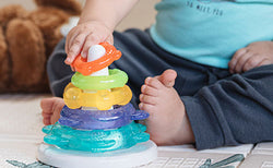 Close up of a sitting toddler playing with the Nuby IcyBite Ocean Rings Teething and Stacking Toy.