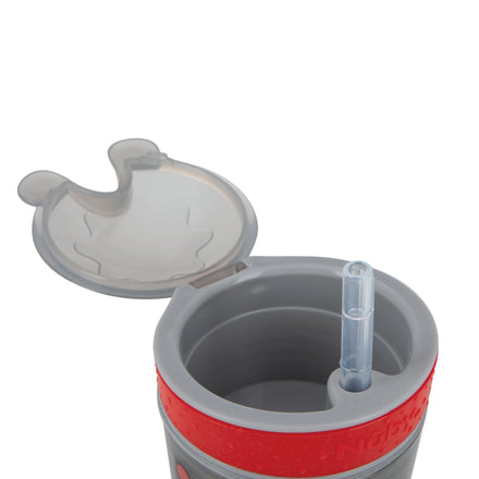 A Snack ’N Sip Cup (2 Pack) | Transportation & Monsters is shown with the lid flipped open, featuring a soft silicone straw. The cup’s exterior displays water droplets, and the design includes gray and red colors.