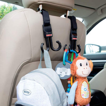 Two Nuby Deluxe Car Seat & Stroller Hooks (2 Pack) are attached to a headrest, holding a gray backpack, an elephant keychain, and a plush monkey toy—ideal for organizing essentials in your car or stroller.