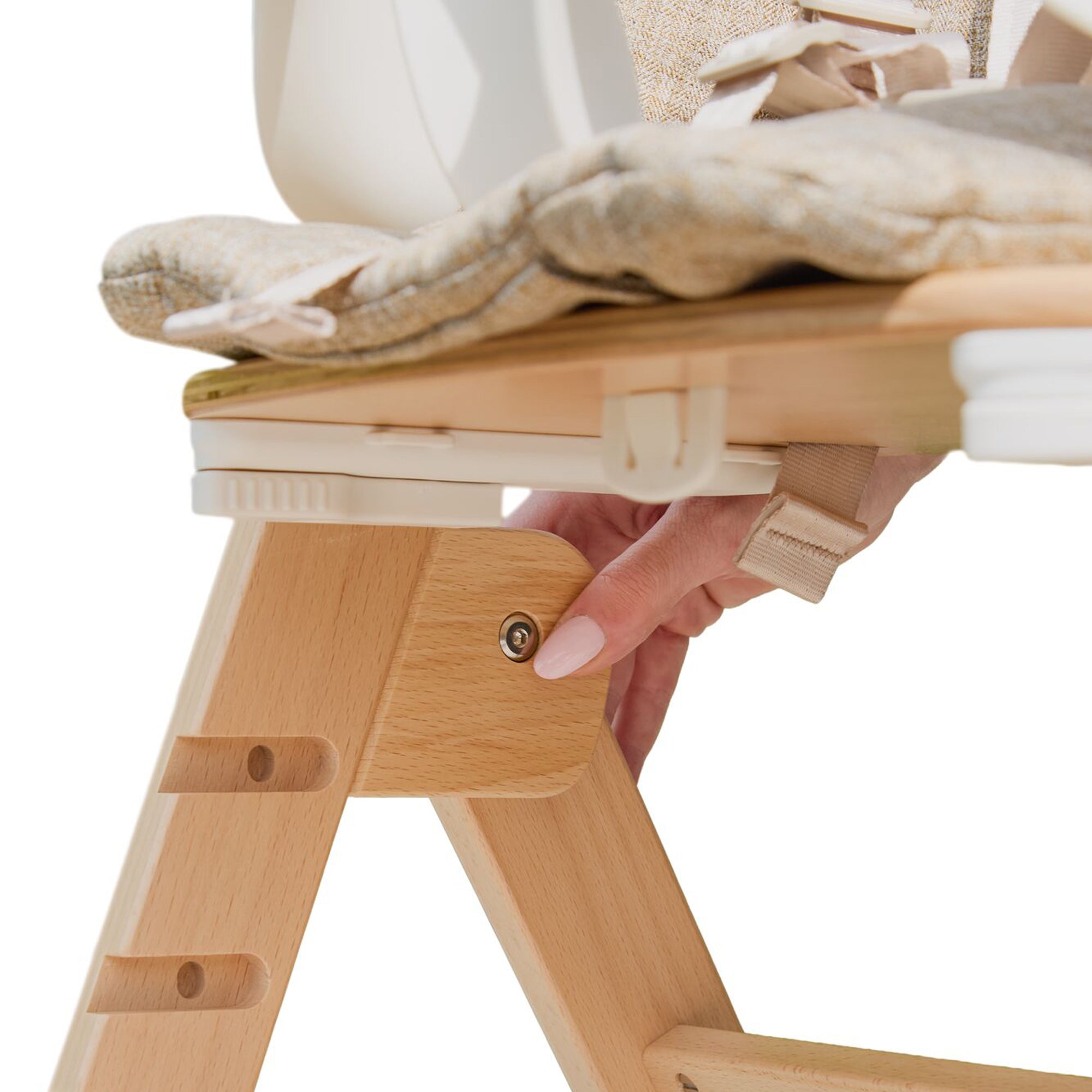 A hand adjusts a bolt on the side of the Grow with Me Foldable High Chair, which features a padded seat.