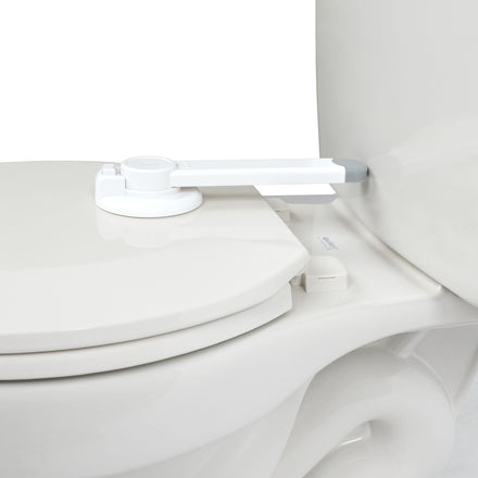 A close-up of a white toilet with the Nuby Safety Toilet Lid Lock | 2 Pack installed between the tank and lid, designed to enhance child safety by stopping children from easily opening the lid.