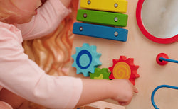 Close up of a toddler playing with the different colored gears on a Nuby Wooden Baby Walker.