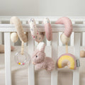 The Animal Adventures Spiral Activity Toy | Bunny features pastel colors, a plush bunny, bead rattle, and yellow-pink rainbow. It hangs on a crib with neutral bedding in the background. Ideal for infant development.