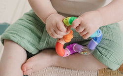 Close up of a toddler playing with a Nuby Twista Rattle Teether Toy.