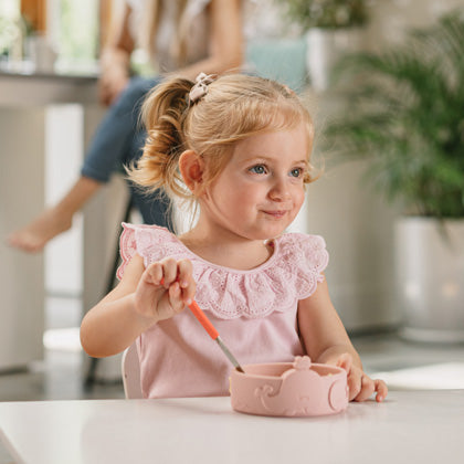 Young girl eating lunch with her Nuby bowl and utensil.