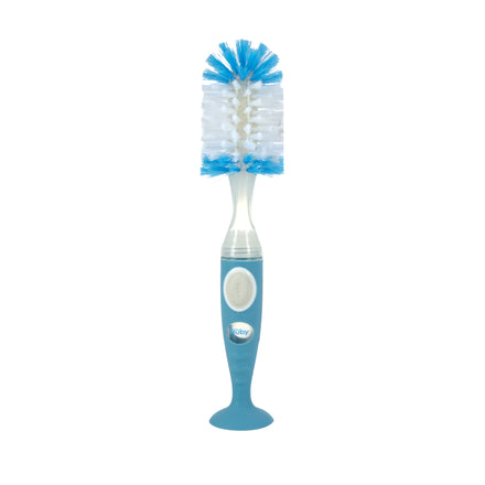 The Nuby Easy Clean Soap Dispensing Brush with Suction Base has blue and white bristles, a blue handle with a white button, built-in soap dispenser for easy cleaning, and stands upright thanks to its suction base.